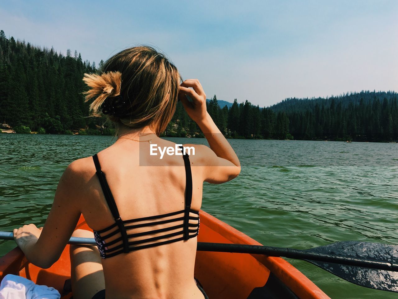 Rear view of woman traveling in boat on river against sky