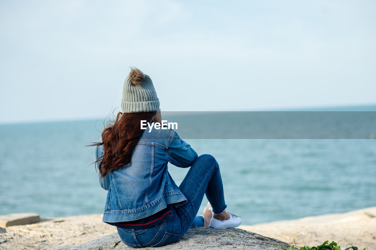 REAR VIEW OF WOMAN LOOKING AT VIEW OF SEA