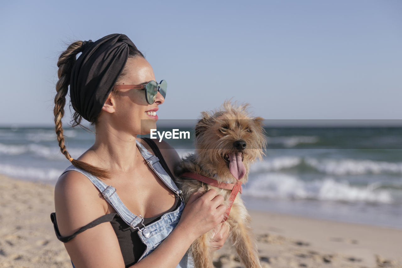 Woman holding her dog on beach