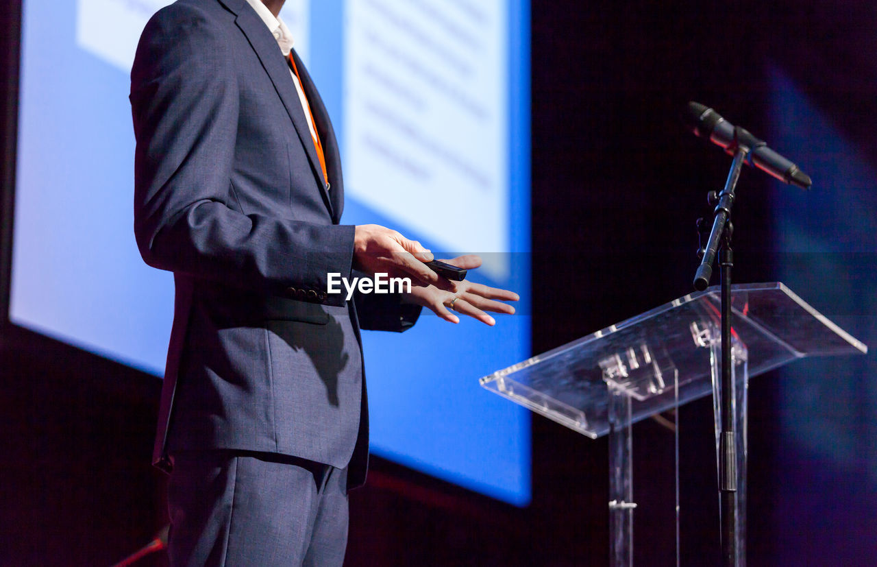 Midsection of man giving presentation at podium