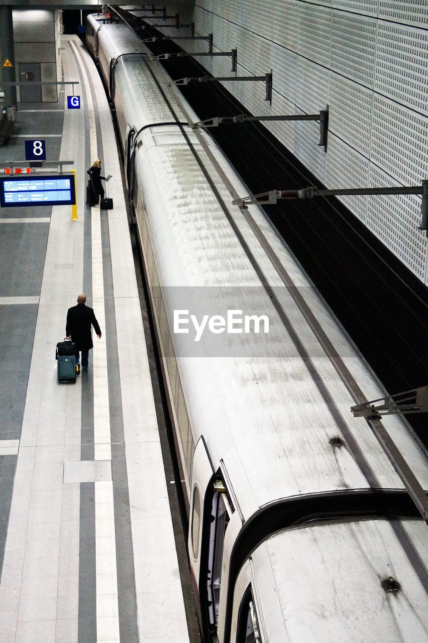 Passengers standing on subway station platform by train