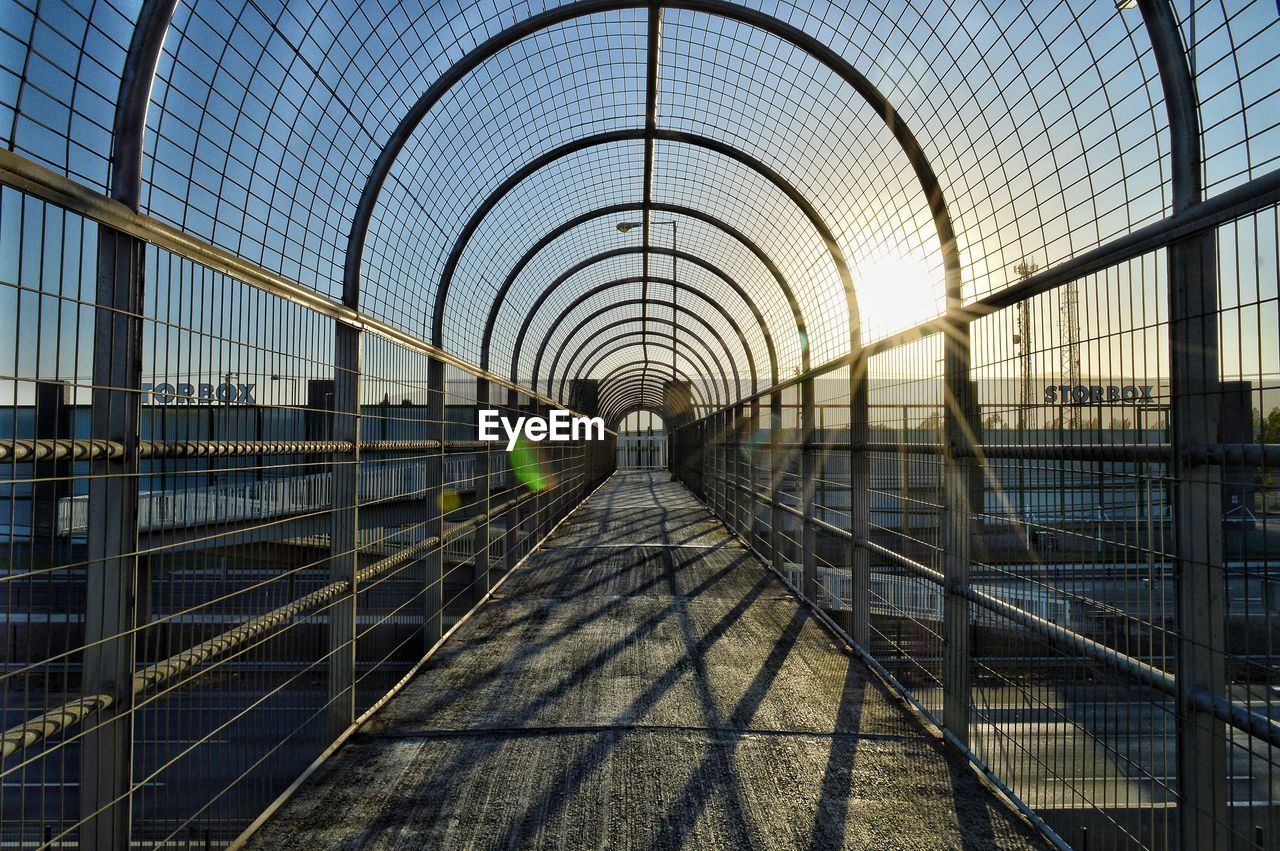 Footbridge in city against sky 