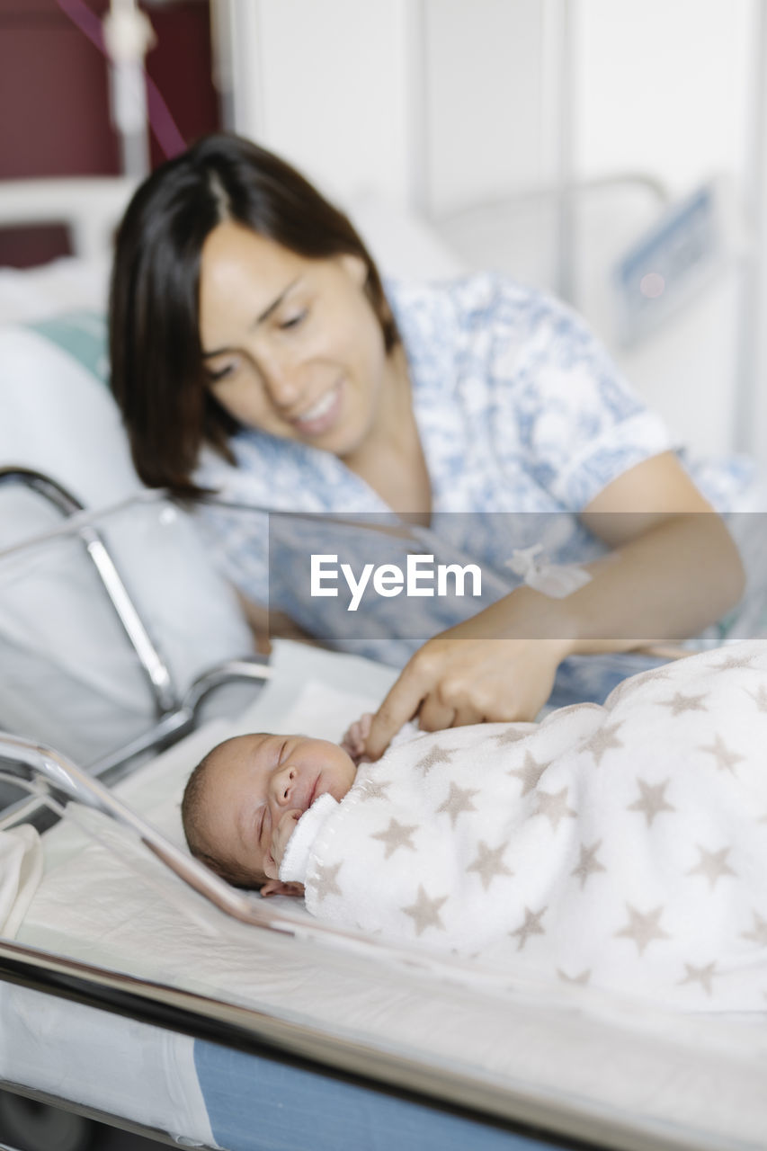 Woman with sleeping newborn baby in hospital