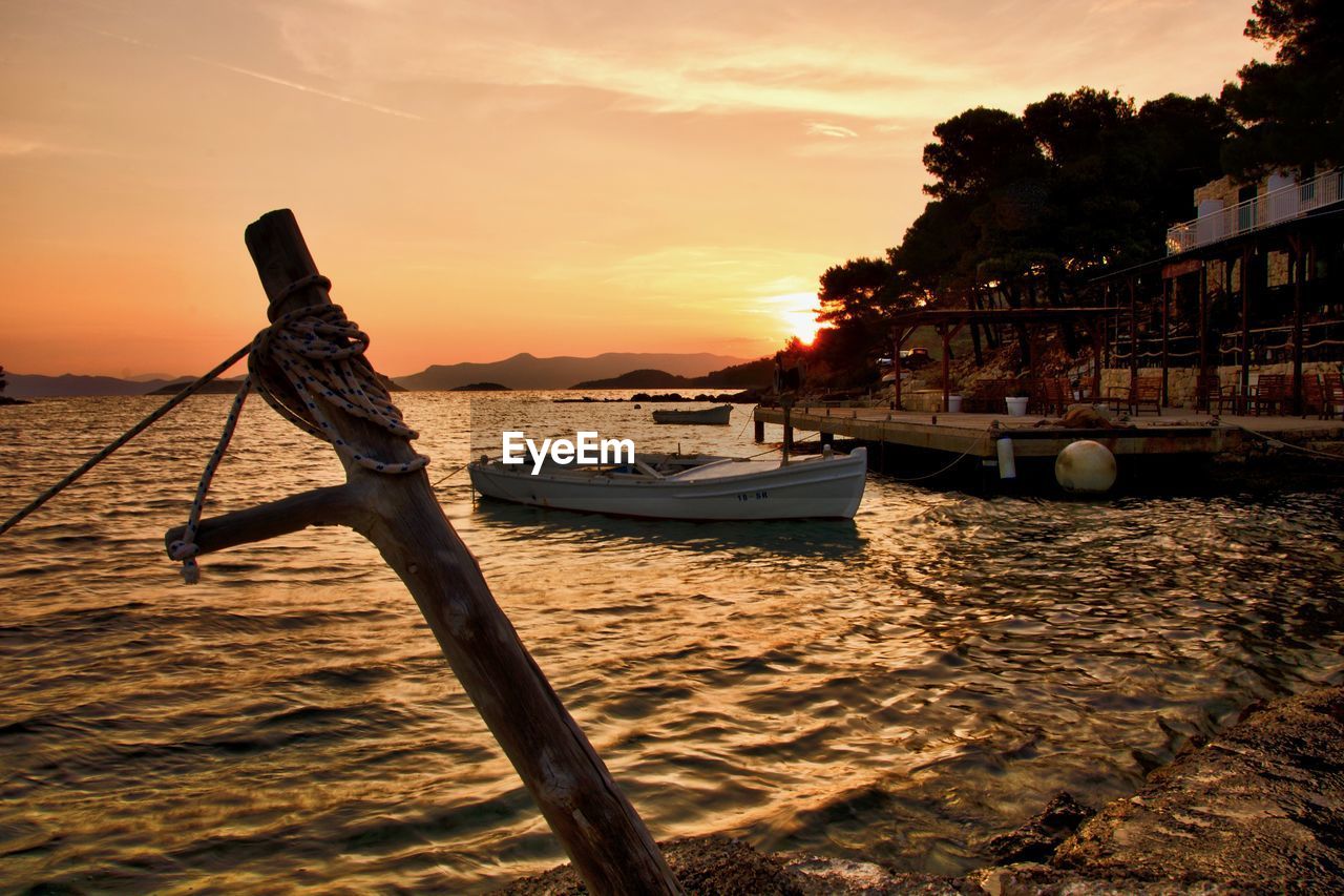 BOATS MOORED ON SEA AGAINST SKY DURING SUNSET