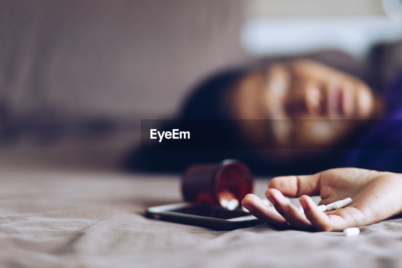 Close-up of woman with medicines lying at home