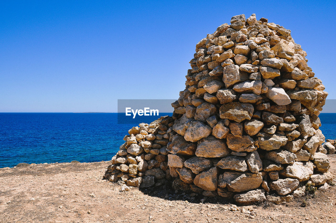 Stack of pebbles on beach against clear sky