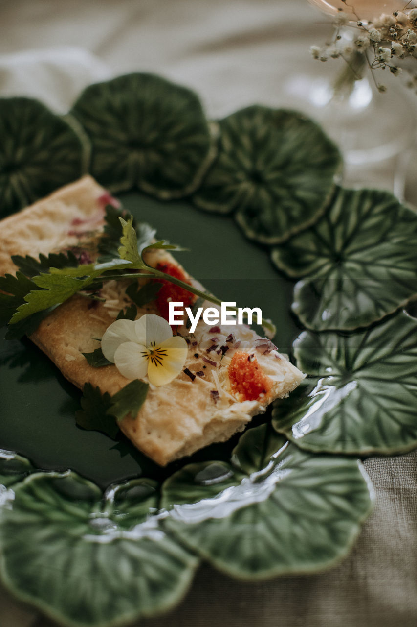 Cracker with herbs and edible flower on plate