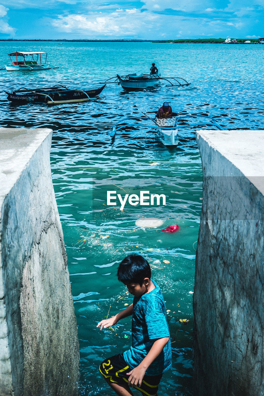 High angle view of boy standing in sea