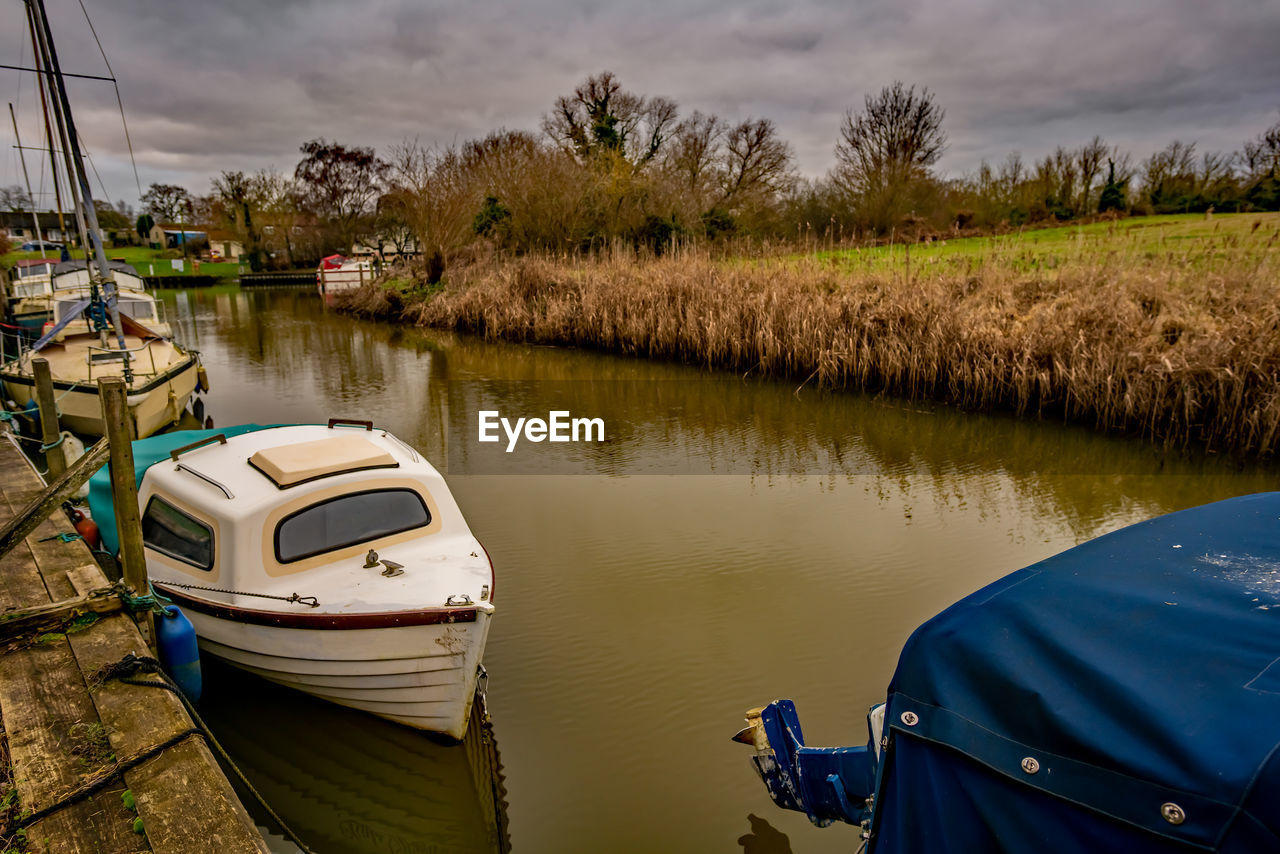 Sailboats moored on lake against sky