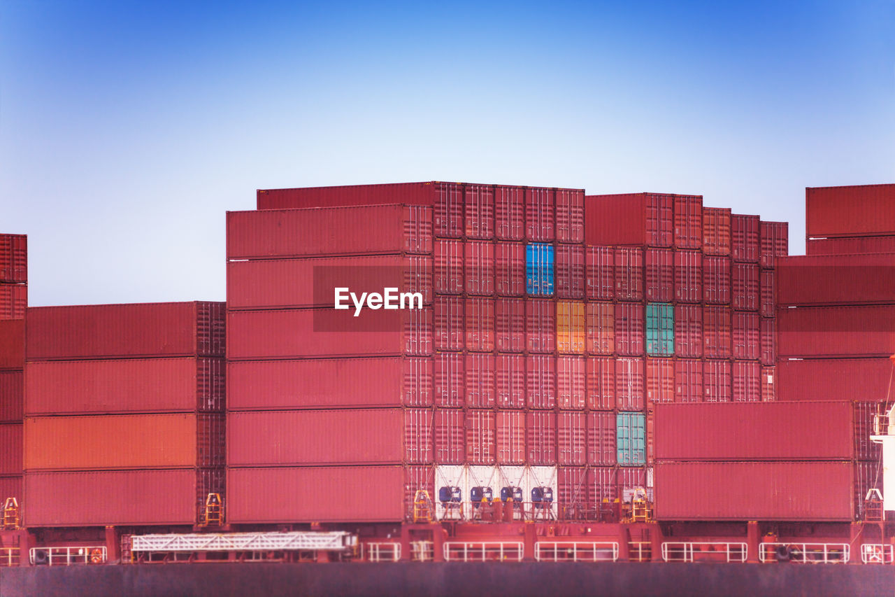 View of stacked container on ship against sky