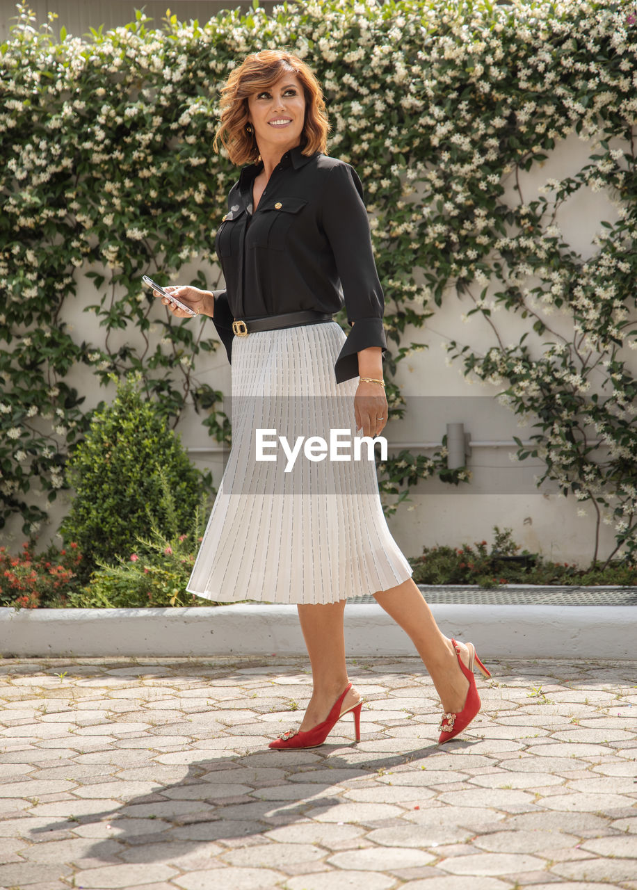 Full length of woman standing against wall