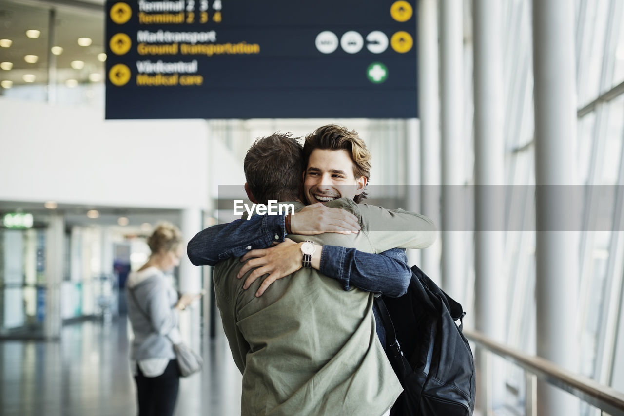 Happy businessman embracing male colleague at airport