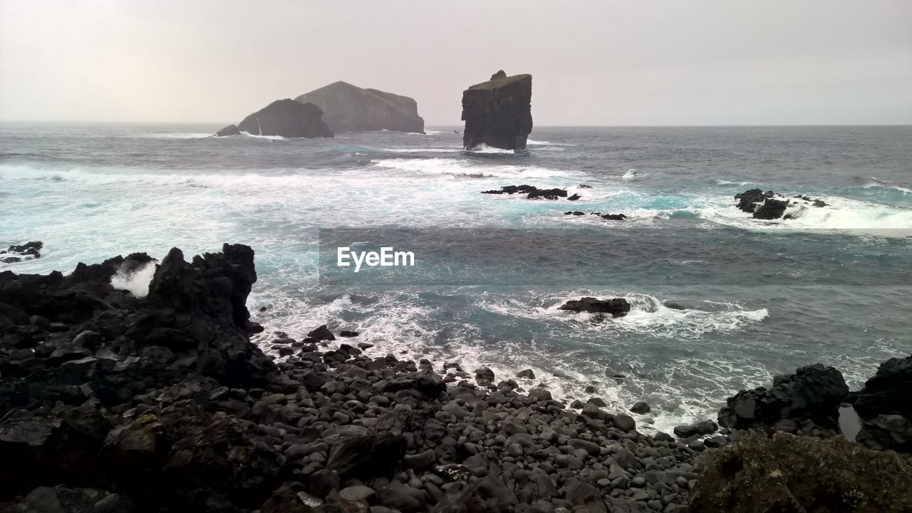 Scenic view of sea and rock formation during foggy weather