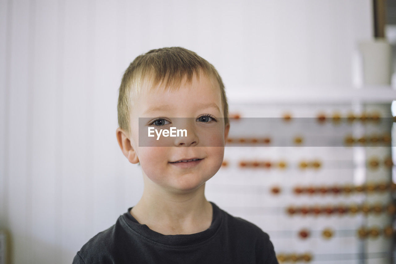 Portrait of smiling boy with blond hair in classroom at kindergarten