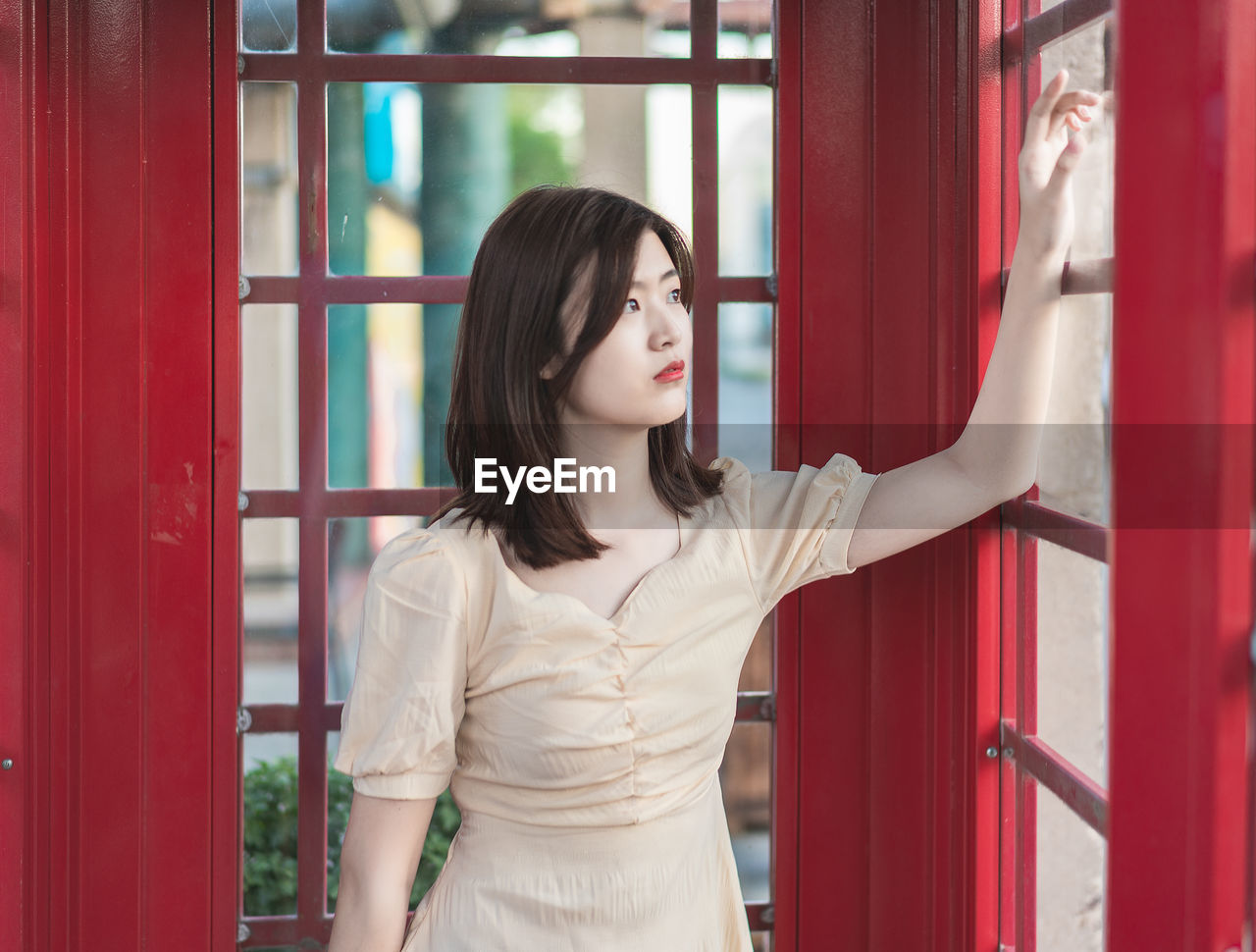 Beautiful young woman looking through window