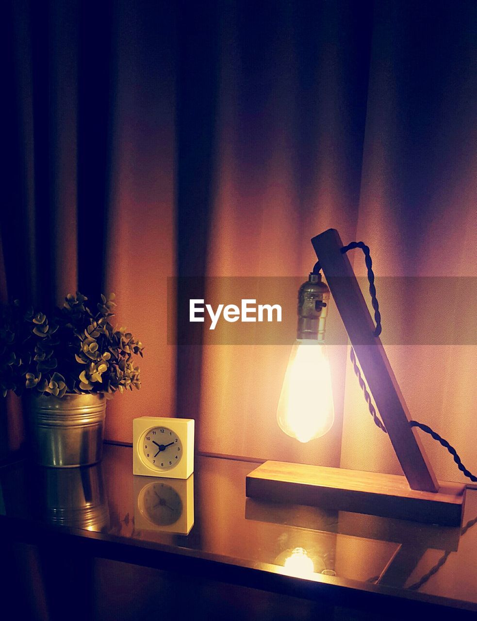 High angle view of alarm clock on table against curtain in room