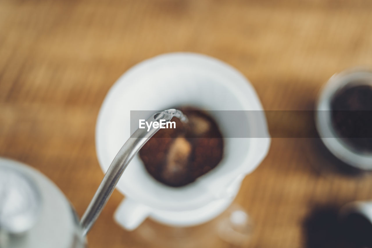 Directly above shot of coffee pouring in cup on table