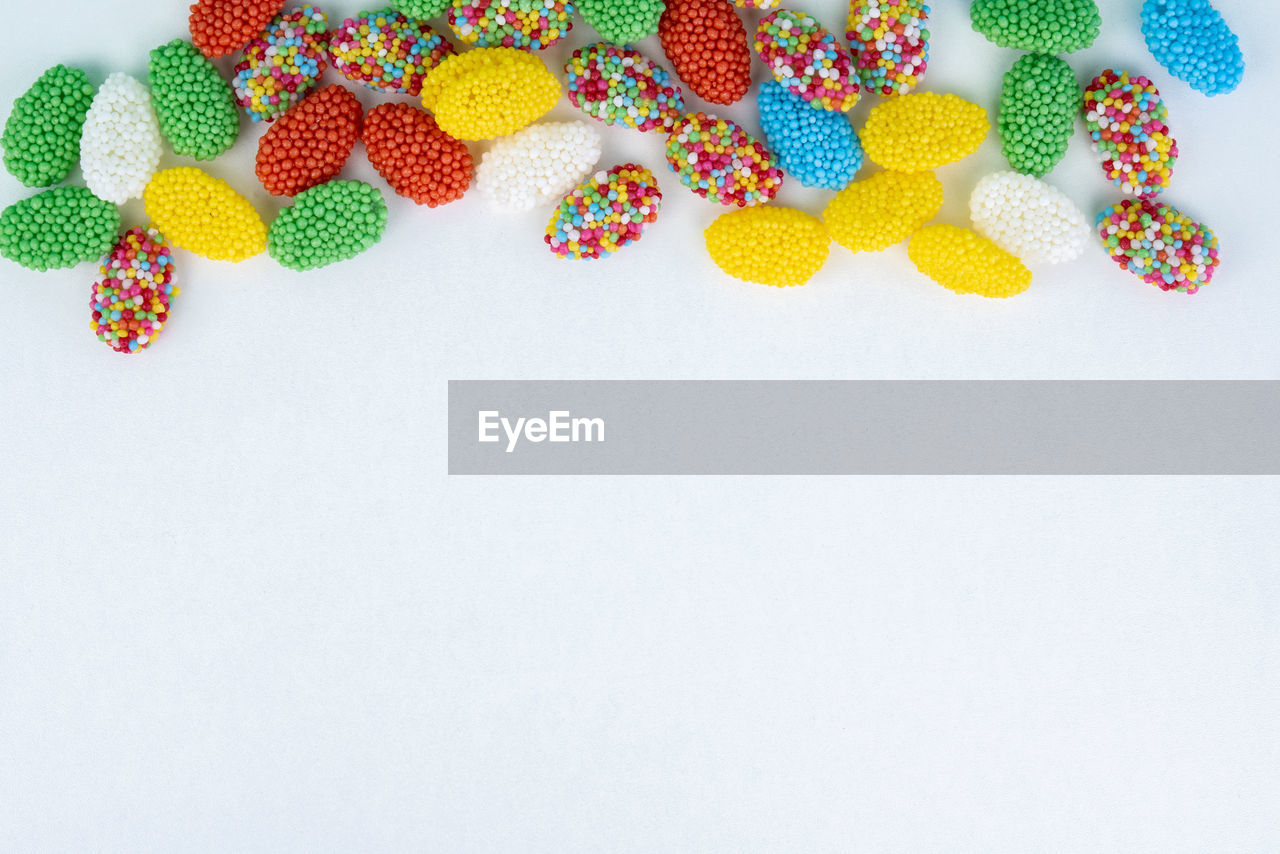 High angle view of colorful candies on white background during easter