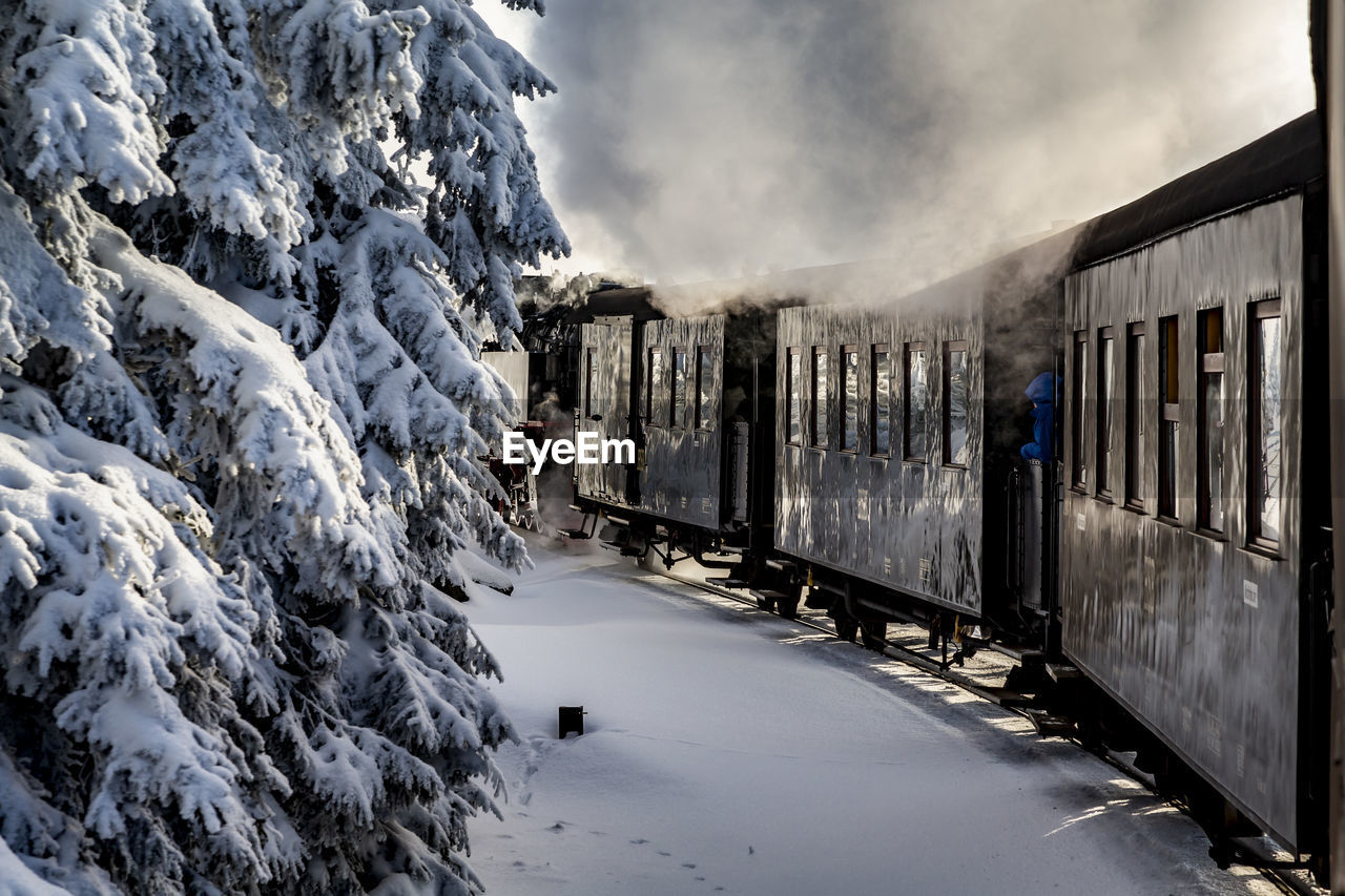 Train on snow covered field against sky