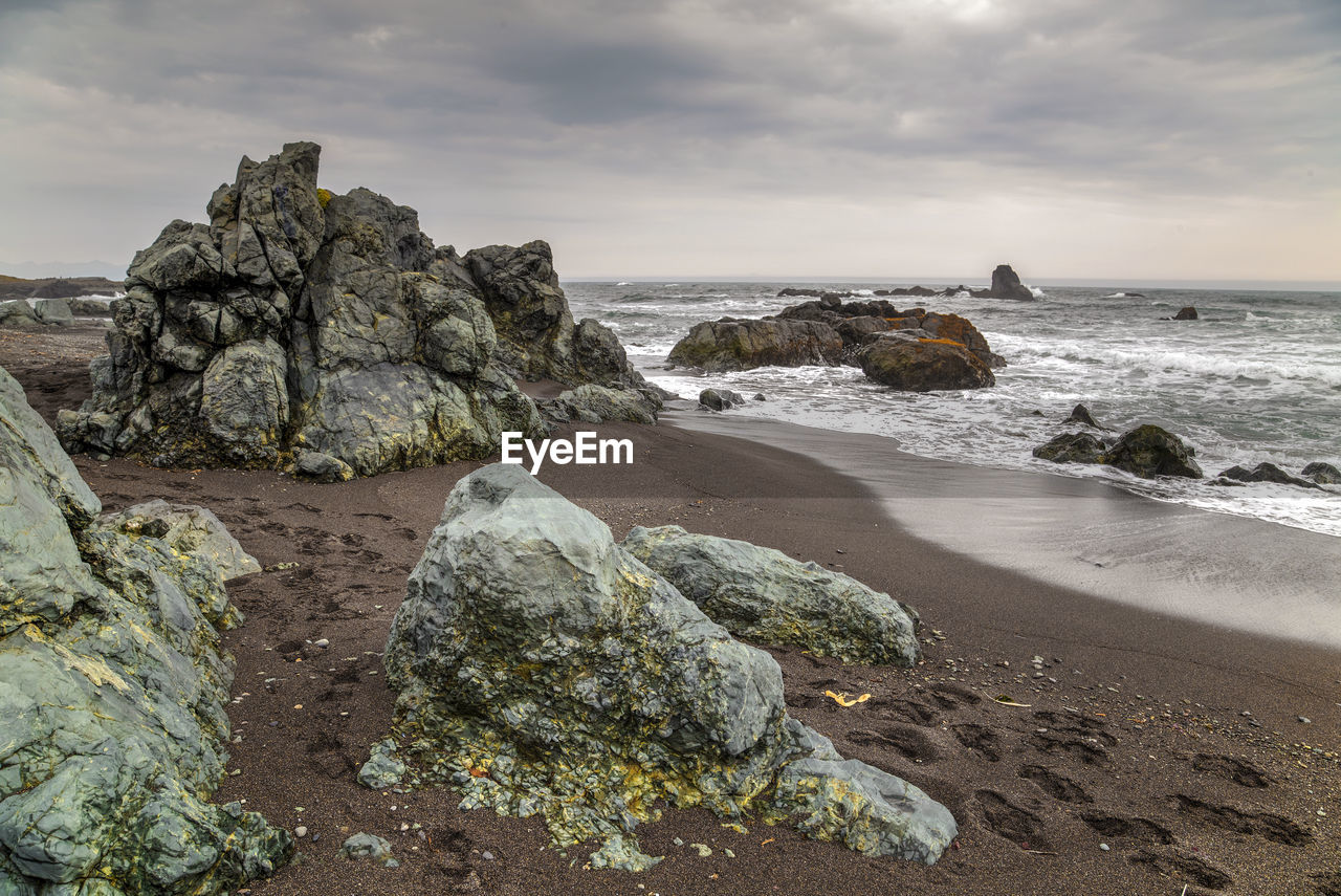 sea, land, rock, beach, water, sky, cloud, shore, nature, coast, ocean, beauty in nature, scenics - nature, body of water, wave, coastline, environment, sand, horizon over water, motion, horizon, landscape, terrain, no people, travel destinations, outdoors, tranquility, cliff, seascape, travel, tranquil scene, rock formation, overcast, wind wave, day, bay, sunset, non-urban scene, water's edge