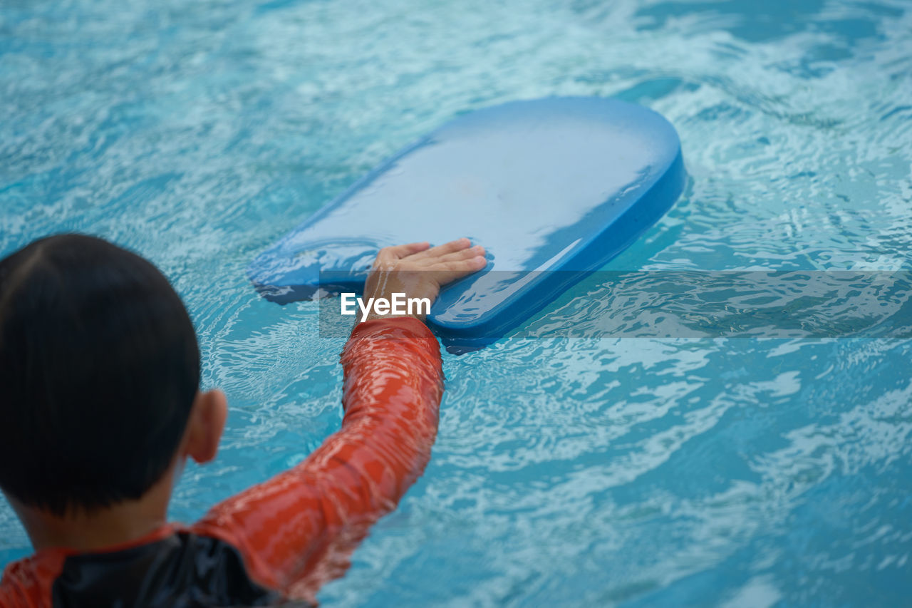 Rear view of boy swimming in pool