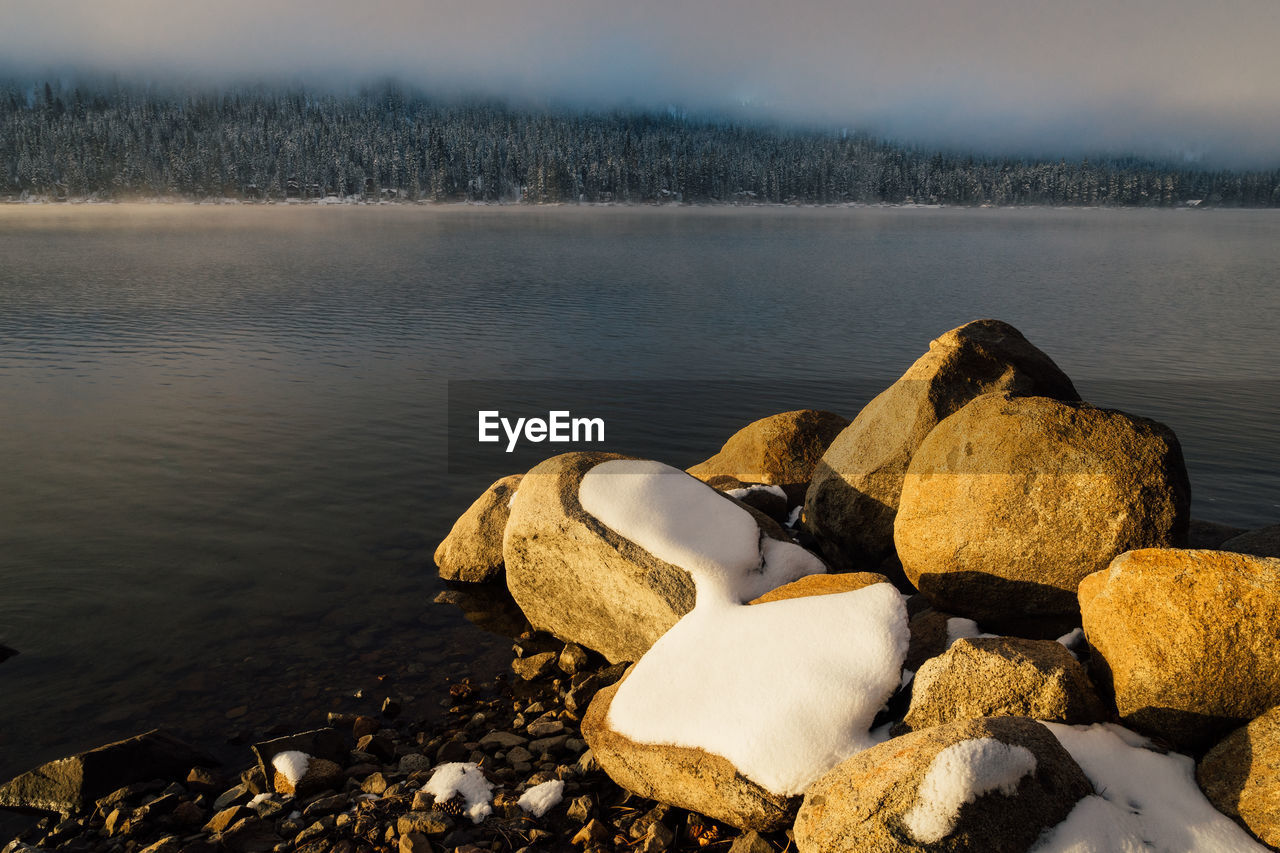 Close-up of pebbles by lake against sky