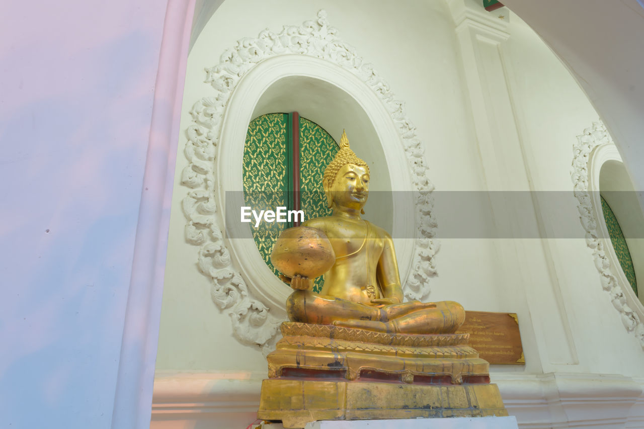 LOW ANGLE VIEW OF STATUE AGAINST BUILDING AND TEMPLE