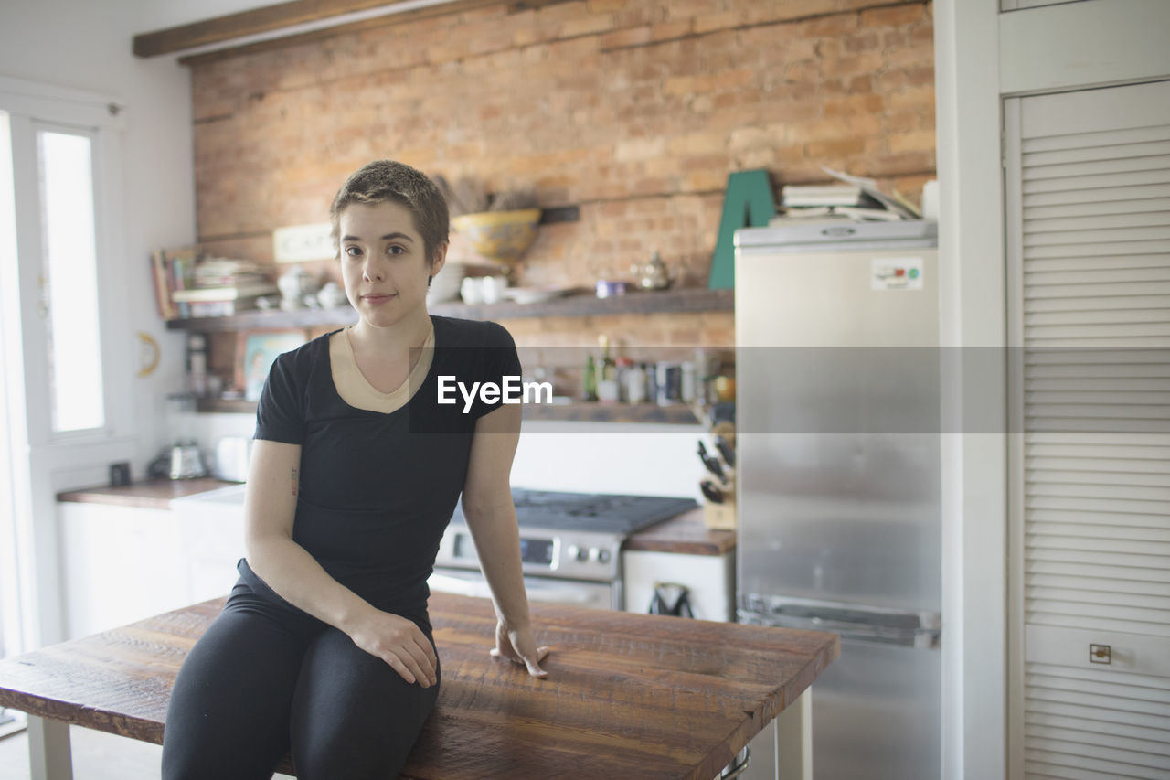 Transgender person sitting on their kitchen counter