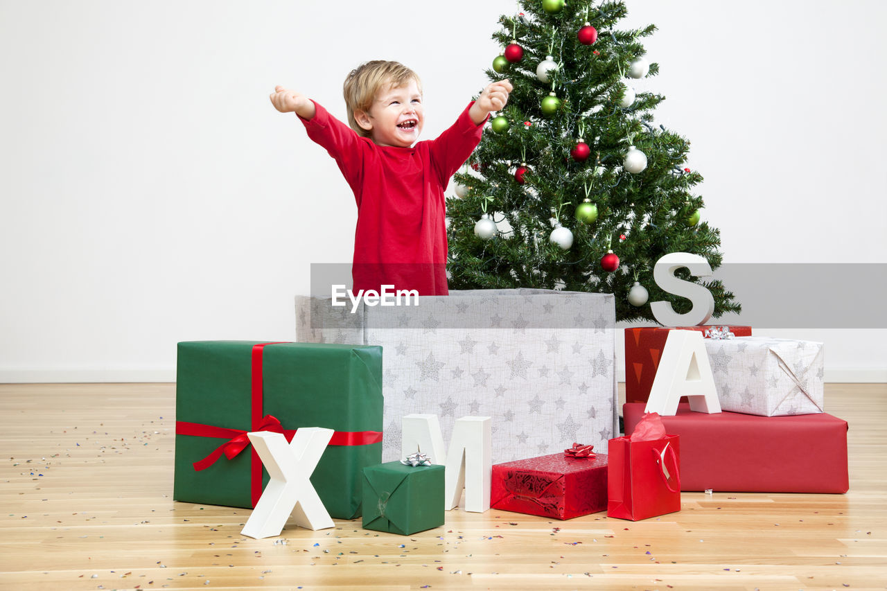 Full length of boy standing against christmas tree