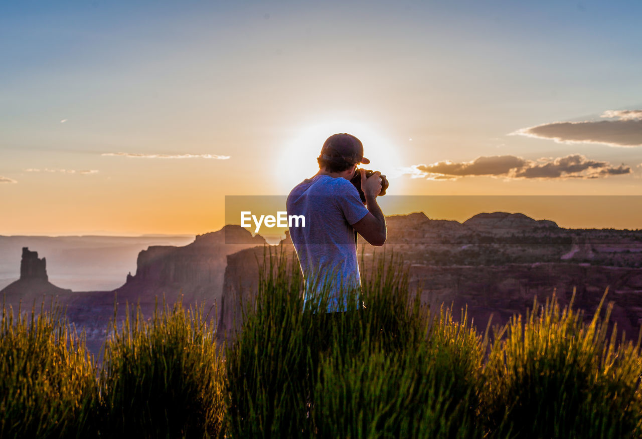 Rear view of man photographing during sunset