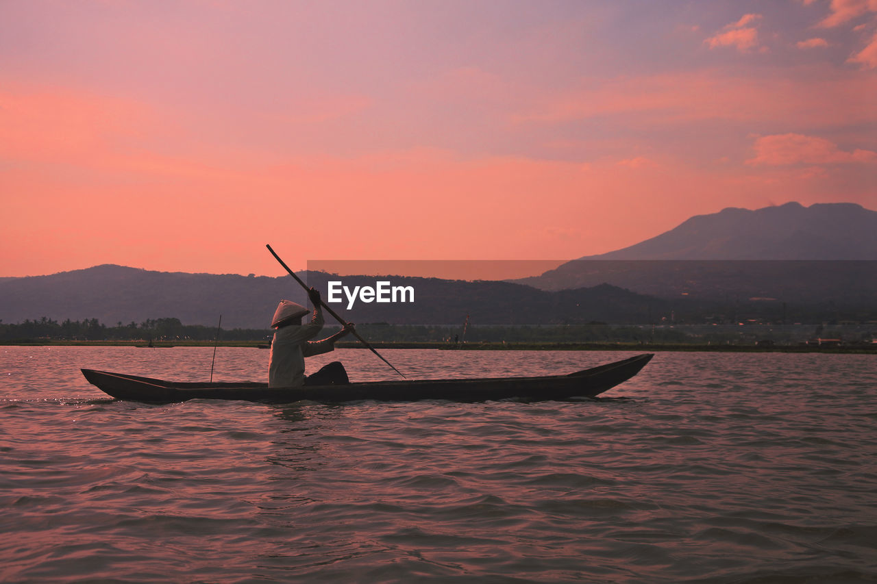 BOAT IN SEA AGAINST ORANGE SKY