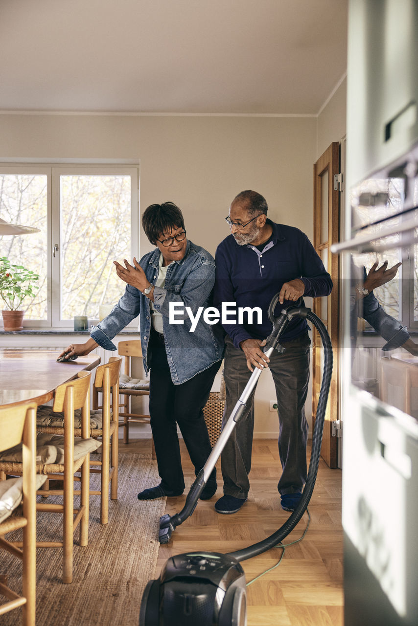 Senior couple having fun while cleaning home