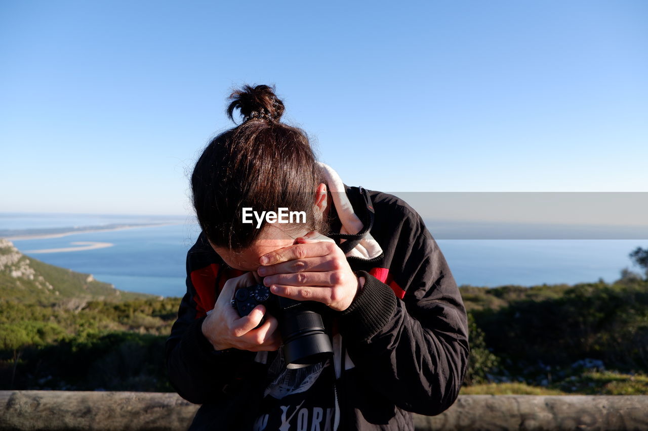 Man photographing against blue sky