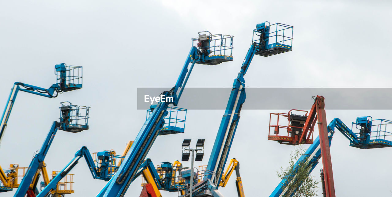 LOW ANGLE VIEW OF CRANES AGAINST SKY IN BACKGROUND