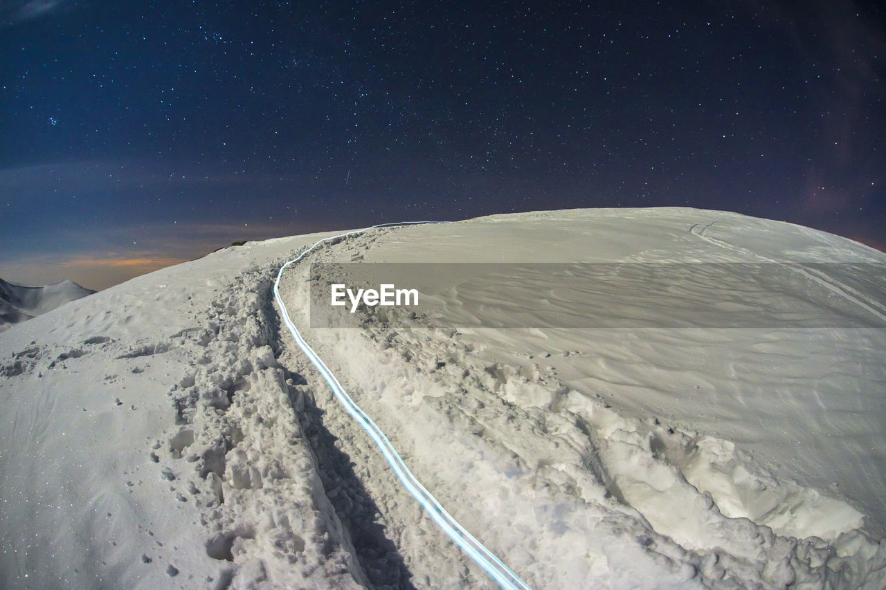 Scenic view of snowcapped mountains against sky at night