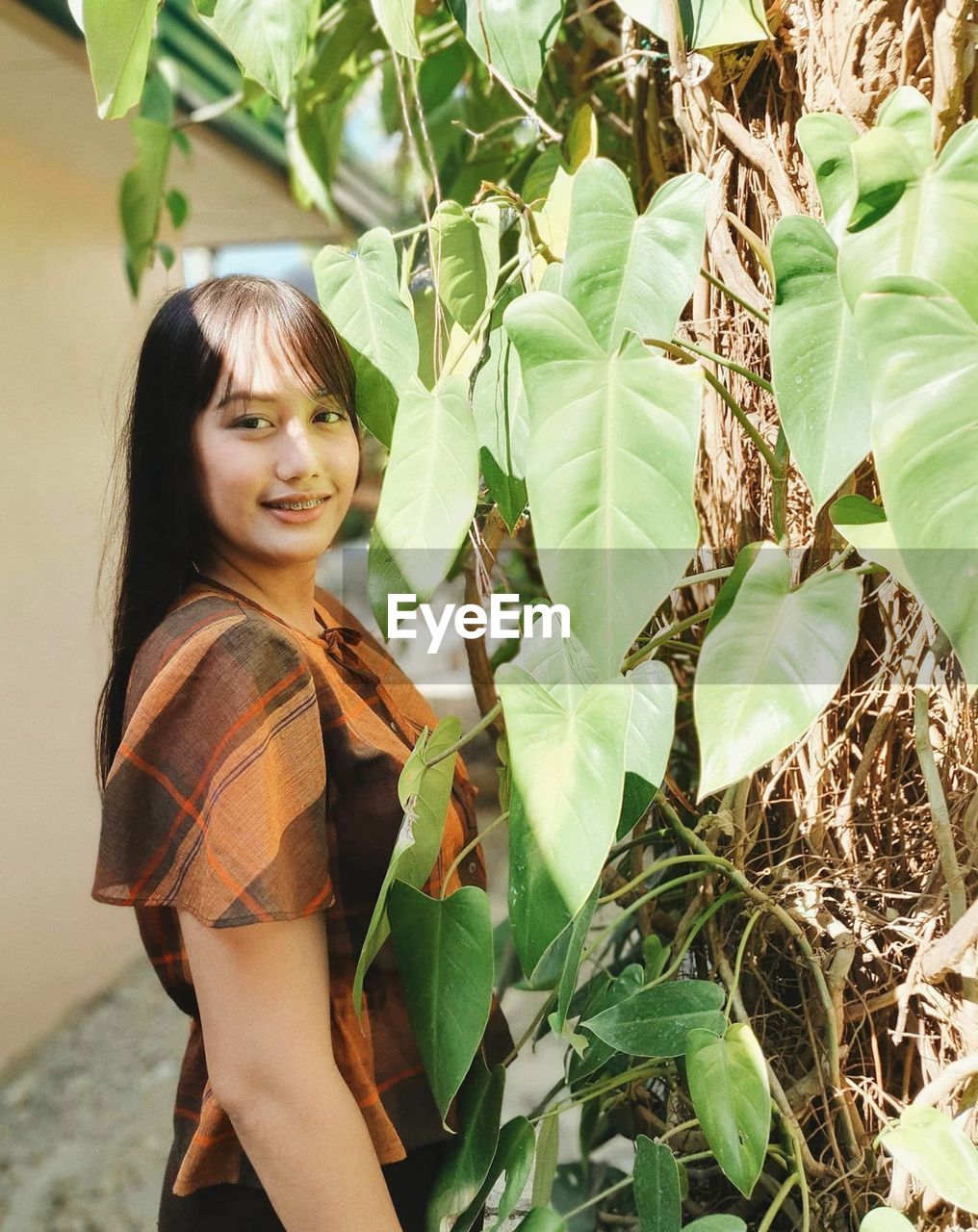 Portrait of young woman standing amidst plants