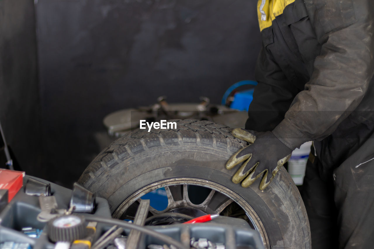 Senior experienced mechanic teaches his colleague how to repair a car