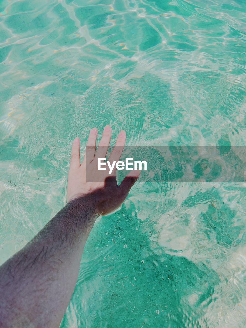 Cropped hand of man against swimming pool