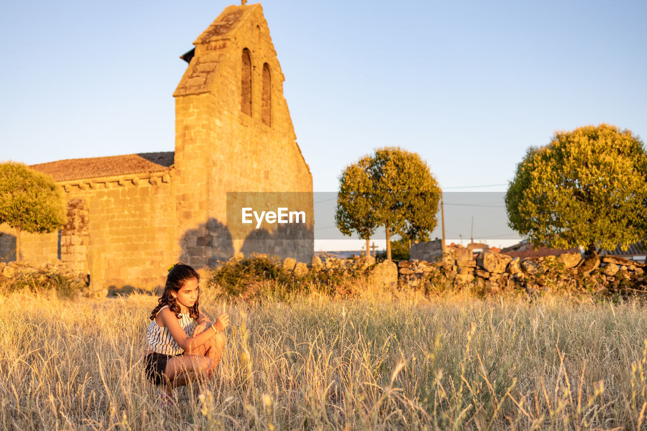 Country girl on a meadow with a church in the background