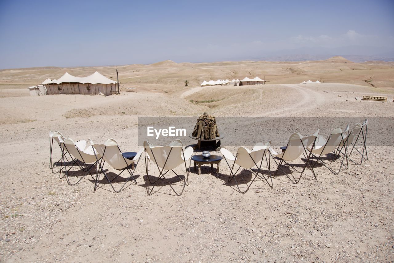 REAR VIEW OF PEOPLE SITTING ON CHAIR AT DESERT