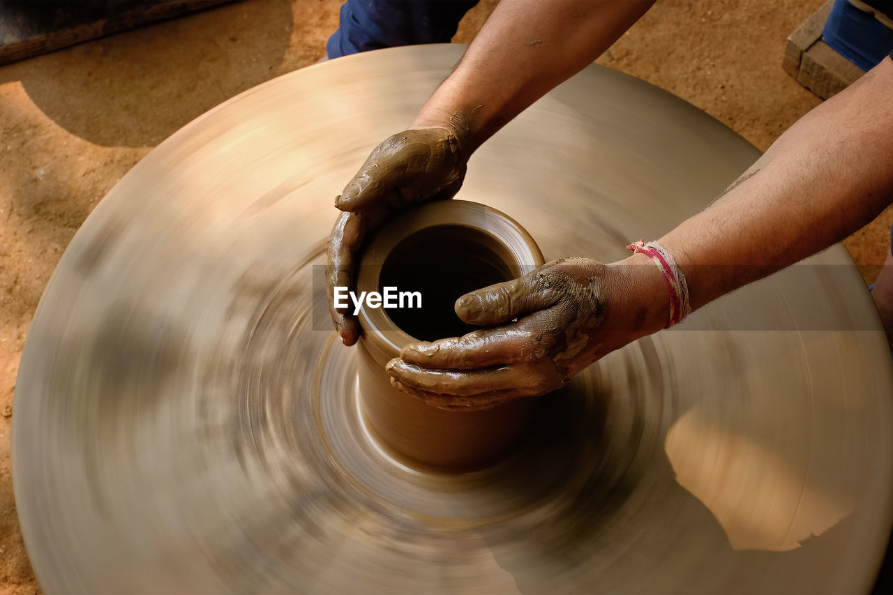 Cropped hands of potter potting pot