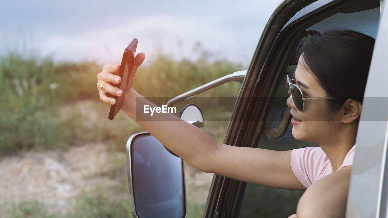 MIDSECTION OF WOMAN WEARING SUNGLASSES WHILE SITTING IN CAR