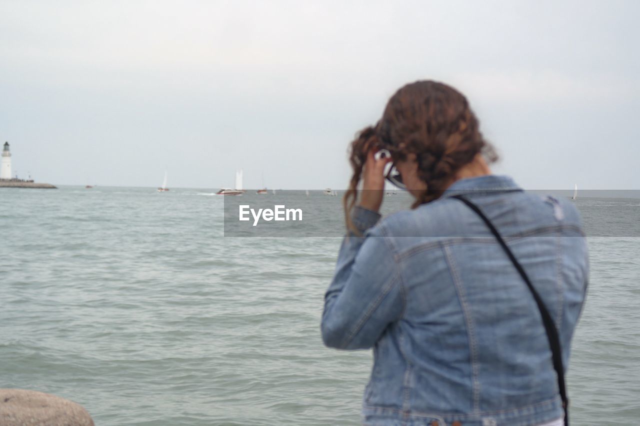 REAR VIEW OF PERSON PHOTOGRAPHING SEA