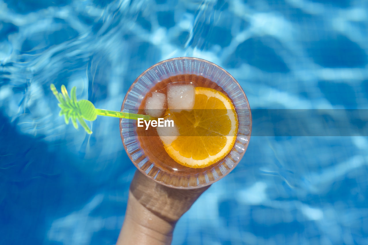 Close-up of hand holding drink at swimming pool