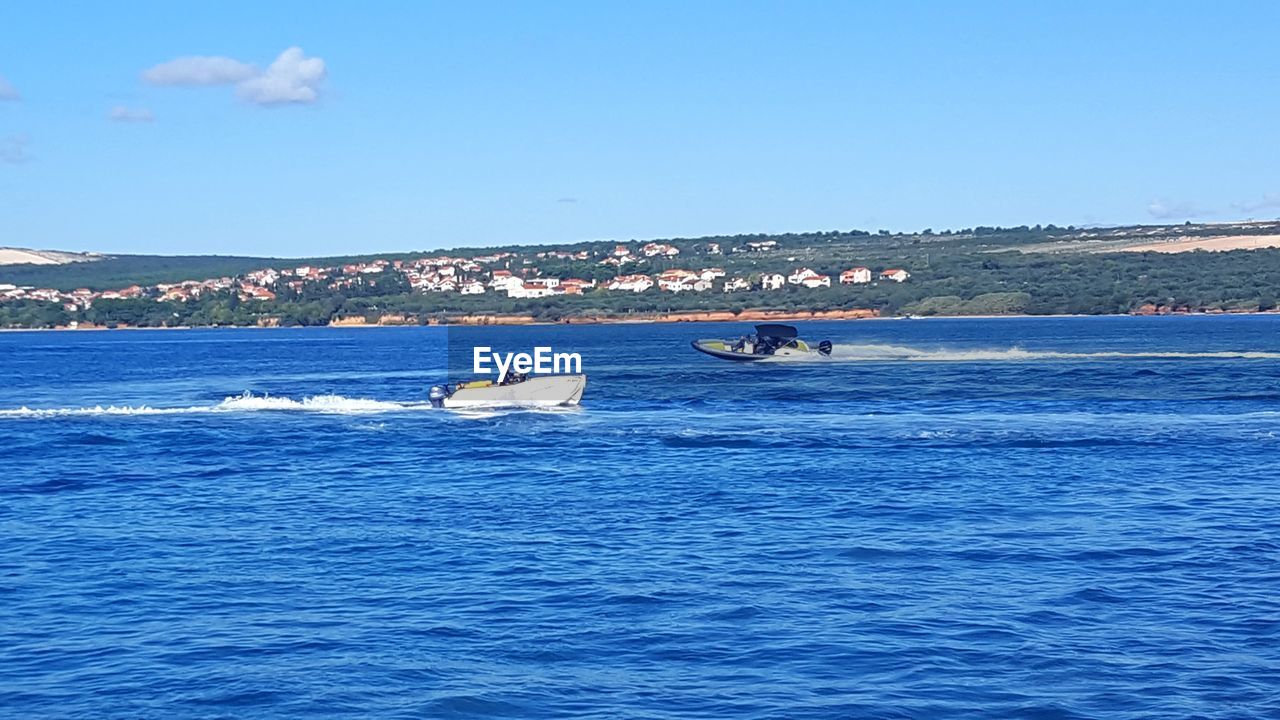 BOATS IN CALM BLUE SEA AGAINST THE SKY