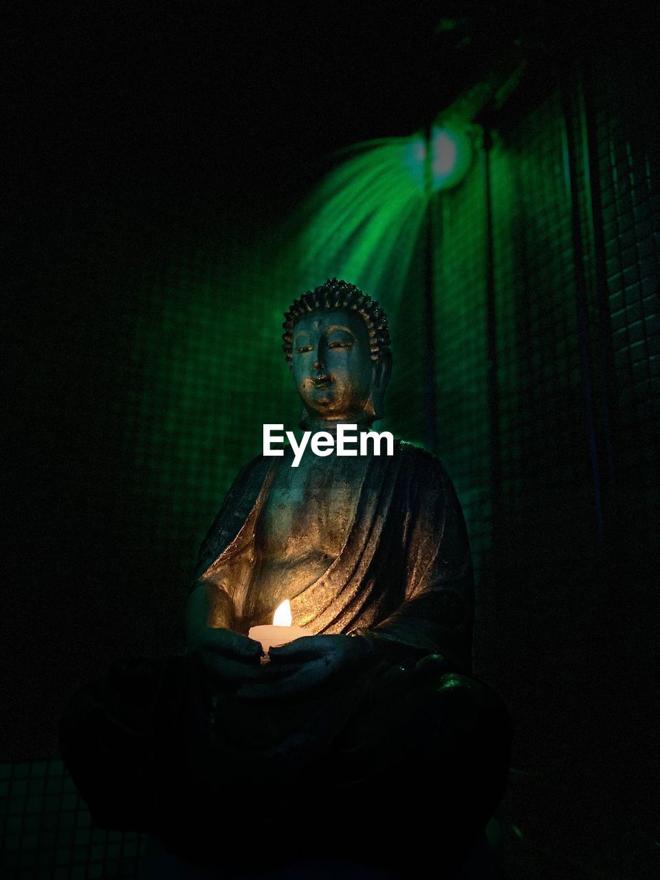 STATUE OF BUDDHA AGAINST ILLUMINATED DARK