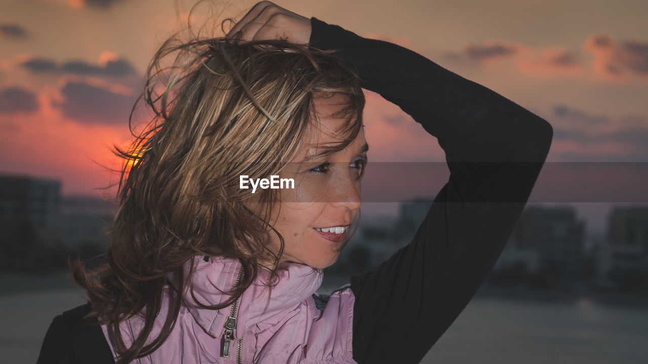 Smiling woman posing against sky during sunset