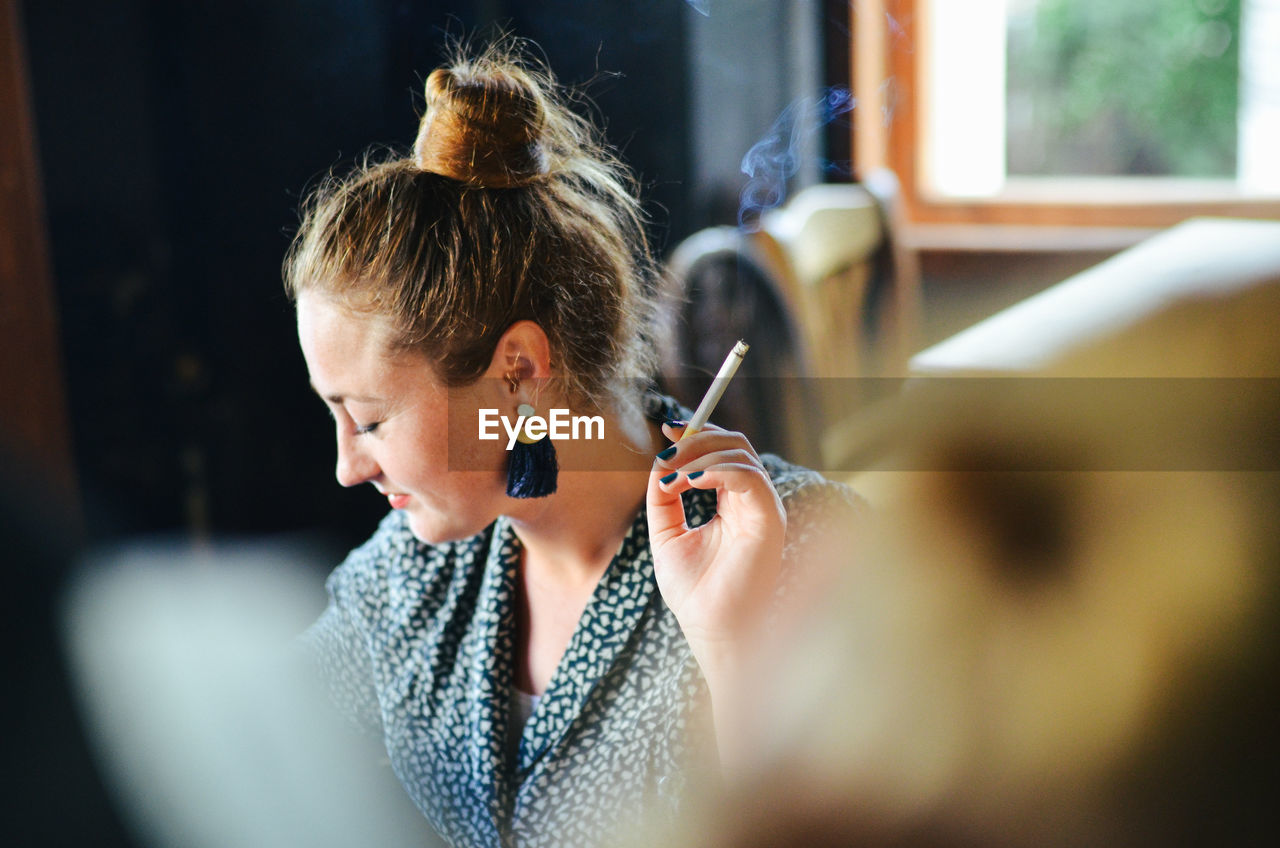 Woman smoking cigarette at home