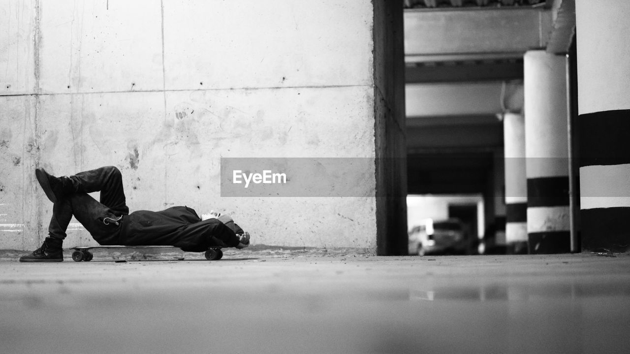 Man lying down on skateboard over floor
