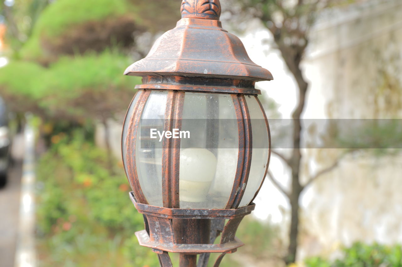 Close-up of vintage lamp with plant as a background